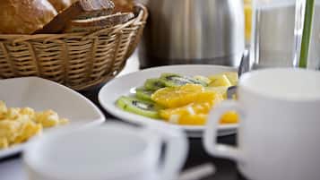 A breakfast table with a plate of fruit, a cup, and a basket of bread.