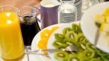 Uma mesa de café da manhã com uma fatia de kiwi, um copo de suco de laranja e um copo de café preto.