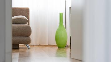 A modern room with a beige sofa, a green vase, and a white door.