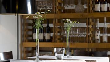 Uma mesa de restaurante com dois vasos de vidro contendo flores e um copo.