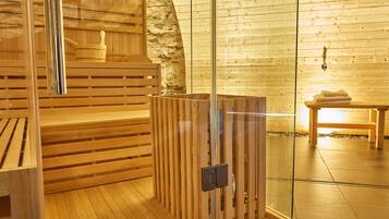 Ein Saunaraum mit Holzbänken, einer Glastrennwand und einer Steinwand.