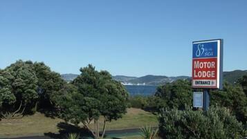 A sign for the Motor Lodge Entrance with a scenic view of the sea and hills in the background.