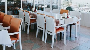 A restaurant with white and orange chairs, a glass table, and large windows offering a view. - Kervansaray Hotel & Pension (Denizli)