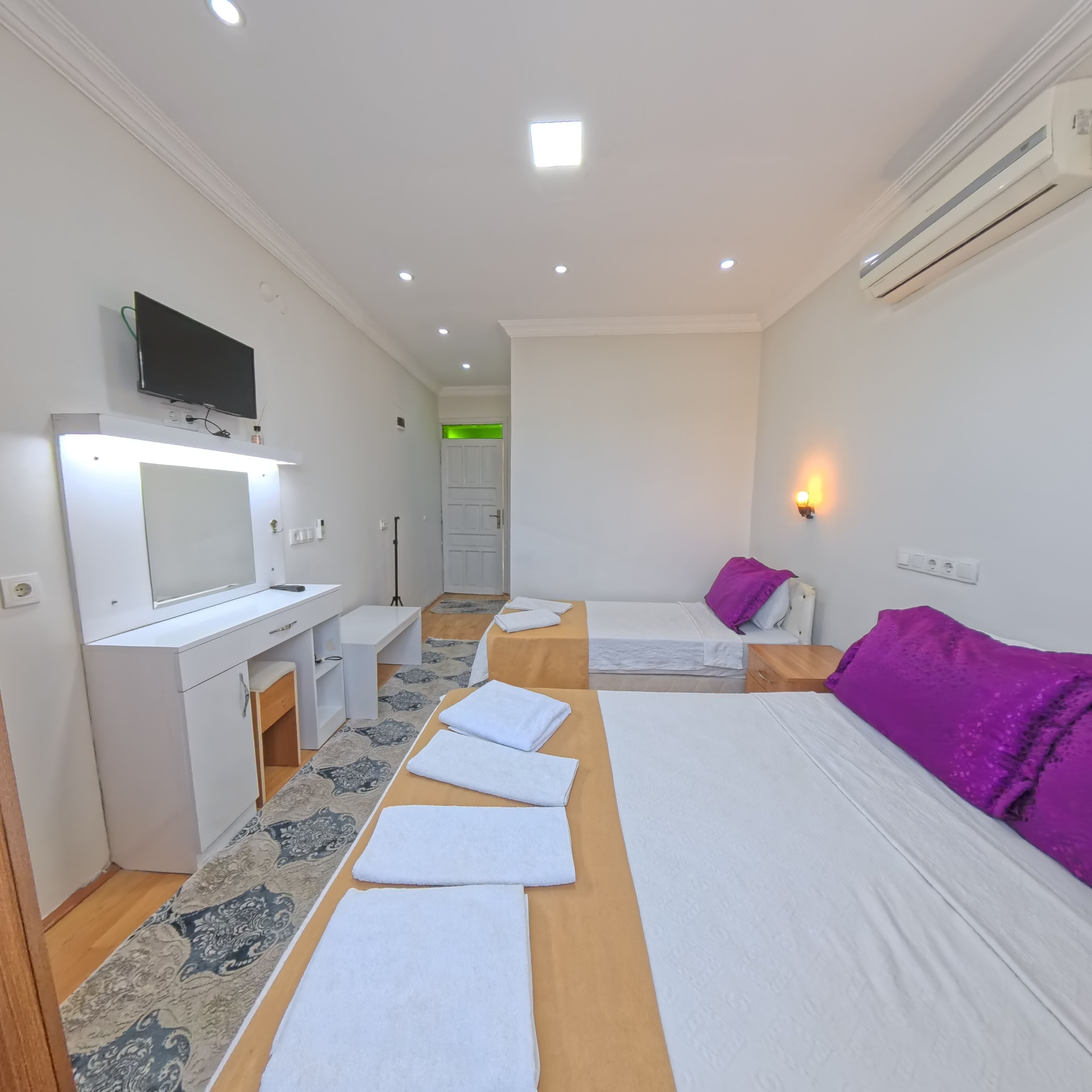 A hotel room with two beds, a desk, a television, and a bathroom visible through an open door.