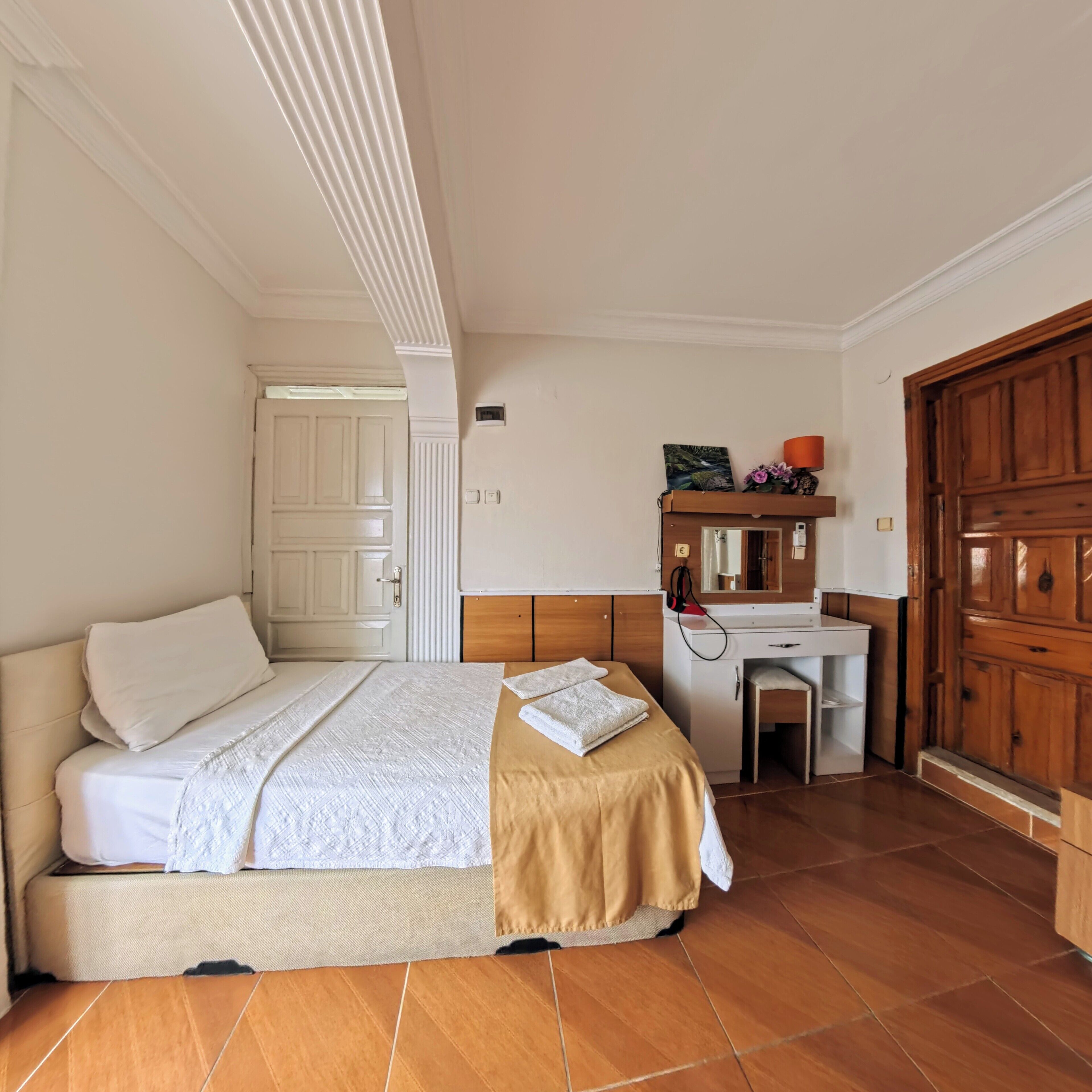A bedroom with a bed, a desk, and a wardrobe.