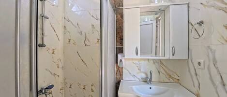 A bathroom with a shower, sink, and mirror.