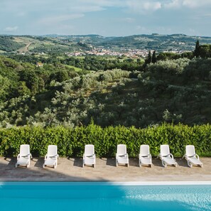 Una piscina al aire libre, sillones reclinables de piscina