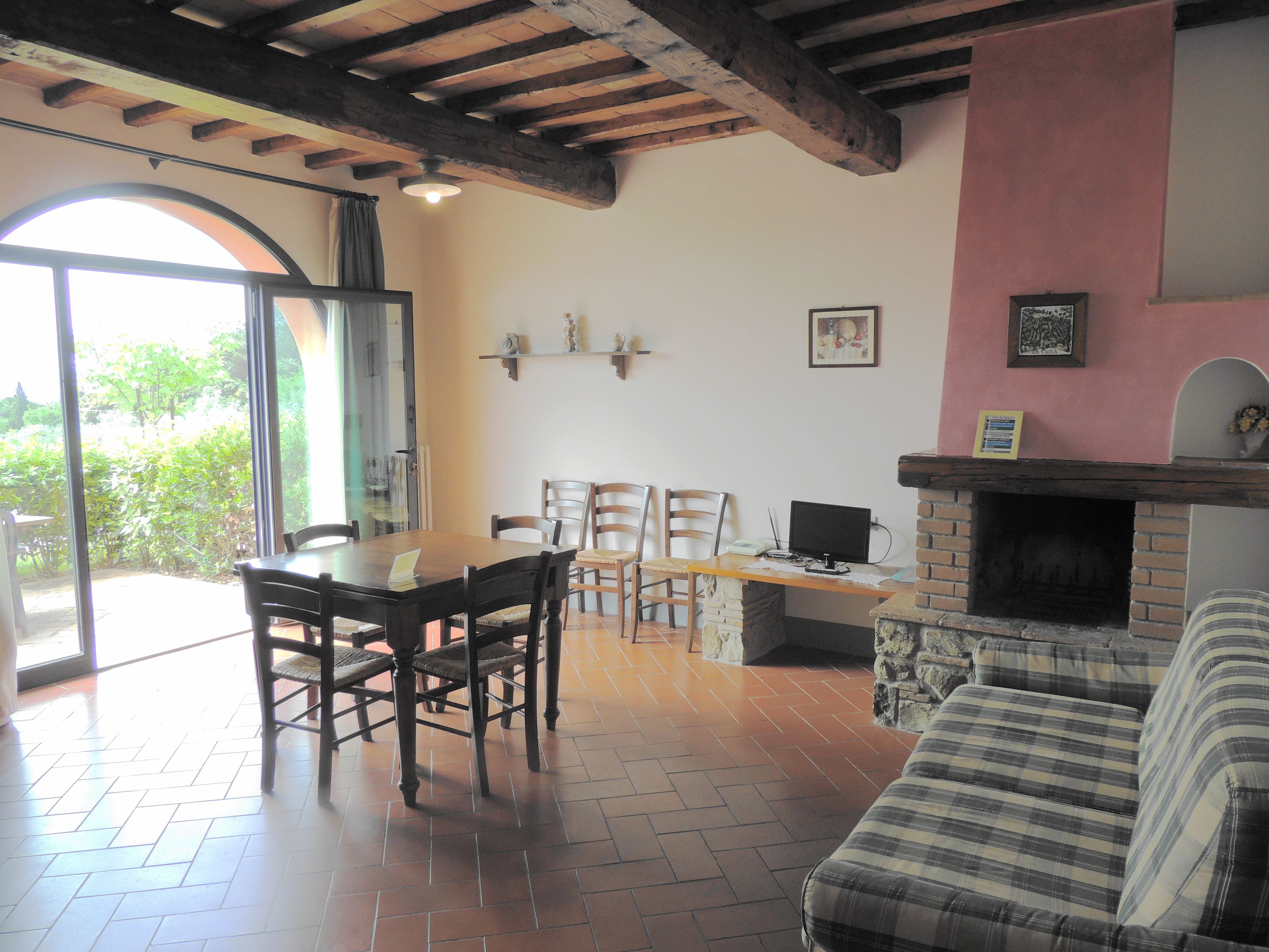 Un comedor con mesa y sillas de madera, una chimenea y vistas al exterior a través de un ventanal.