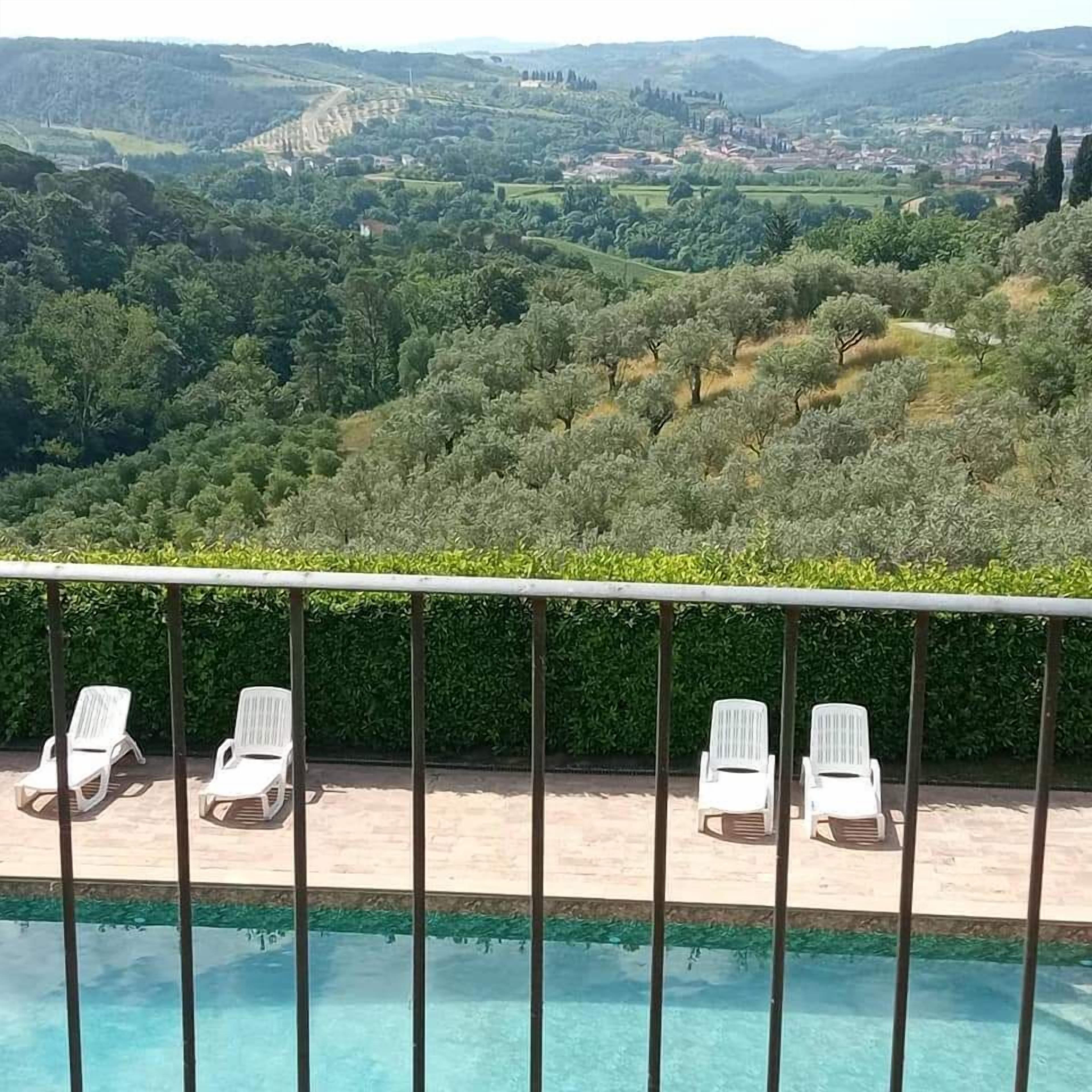 Vista de la piscina con una vista despejada de un paisaje exuberante, con árboles y un pueblo lejano.