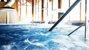 A hot tub with water jets, wooden beams, and a view of the outdoors.