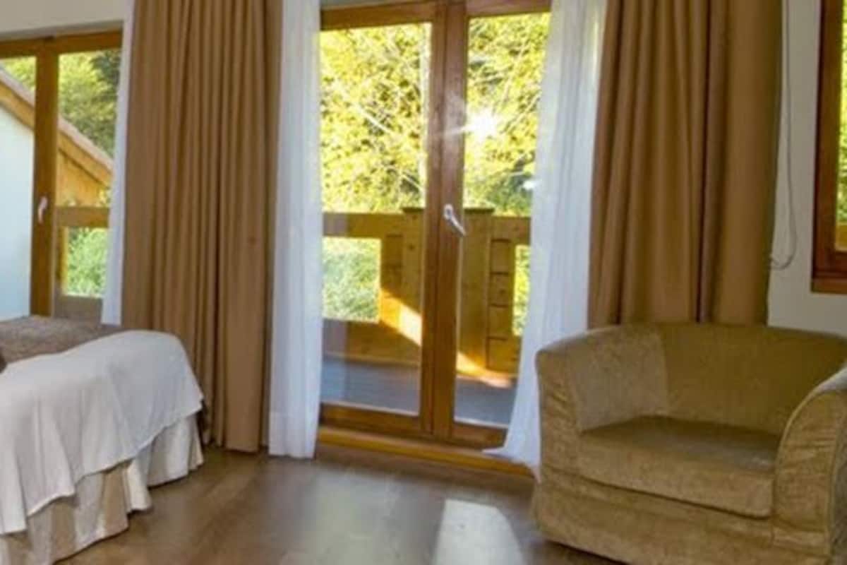 A hotel room with a bed, a striped sofa, and a chair.
