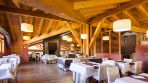 A spacious dining area with wooden beams and tables set for a meal.
