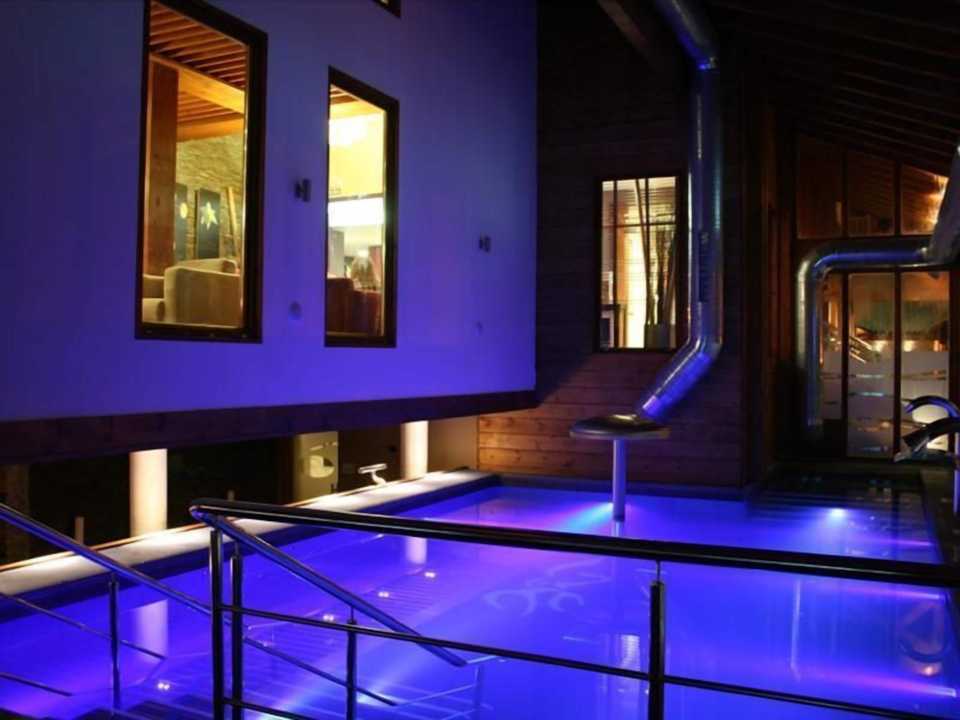 Un espacio de spa con piscina, paredes de madera y una escalera.