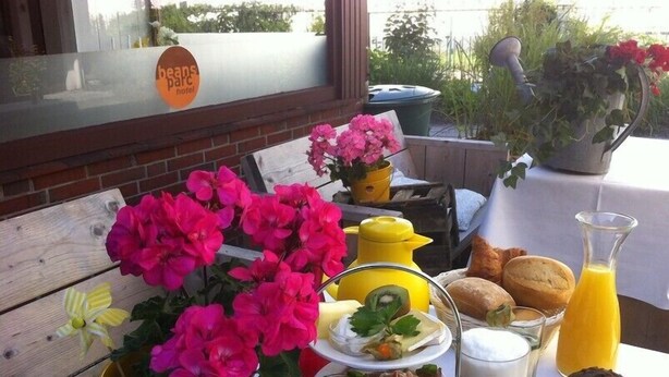 A breakfast setup with flowers, food, and drinks on a table outside a hotel. - Beans Parc Hotel Jade (Wilhelmshaven)