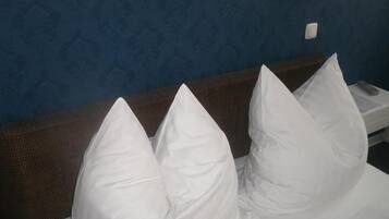 A hotel room with a bed, pillows, a nightstand, and a wall with a textured pattern.