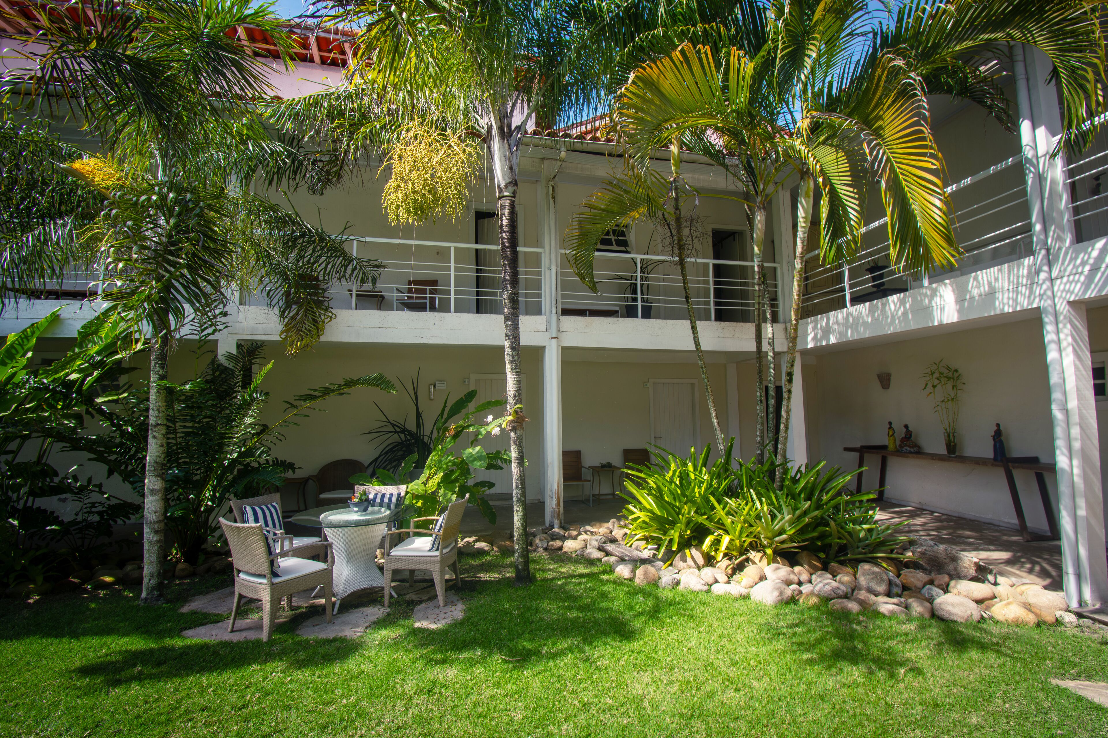 A courtyard with a pool table, chairs, and a small garden area with rocks and plants.