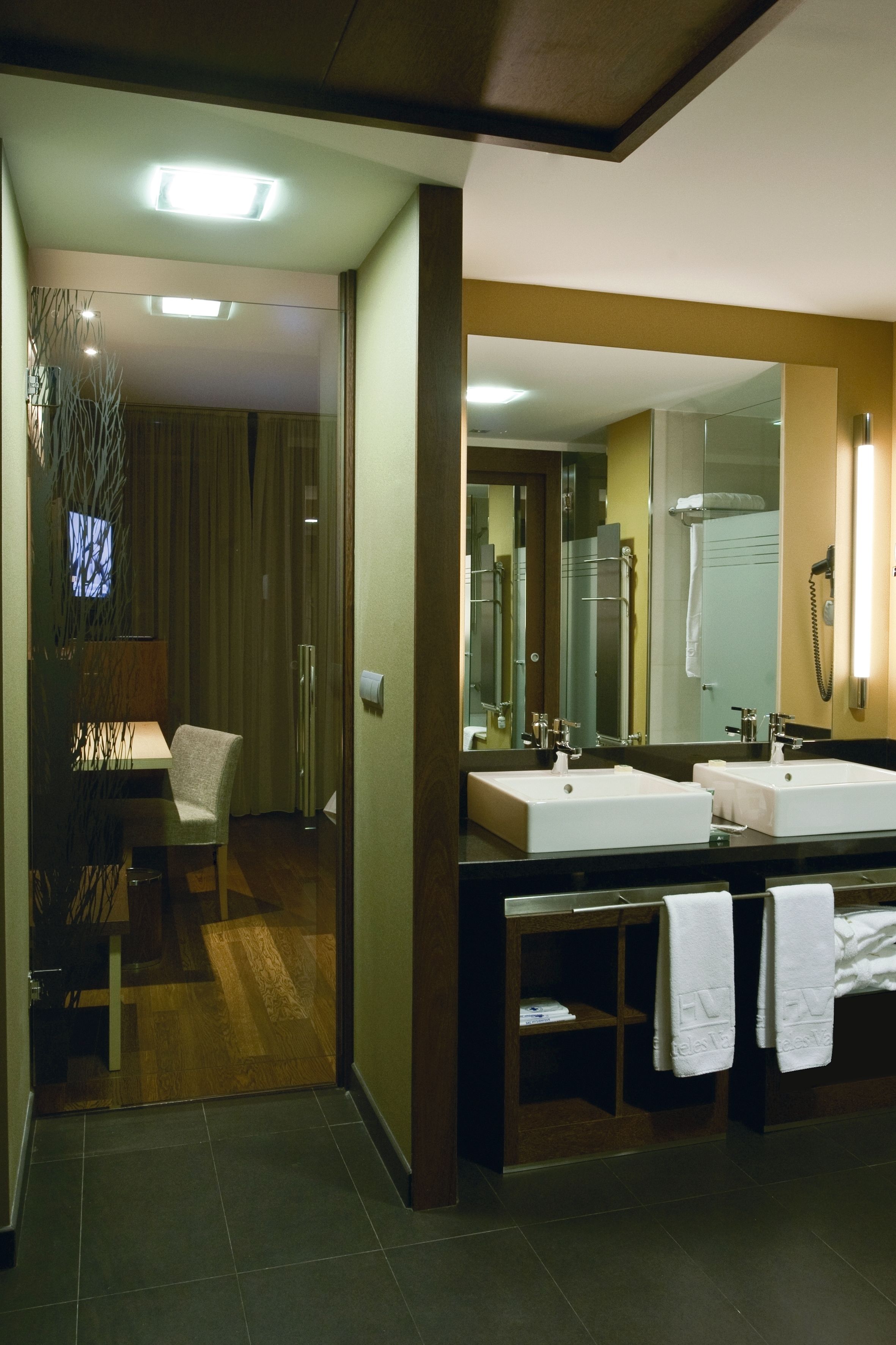 Un baño moderno con dos lavamanos, un espejo grande y una zona de ducha.