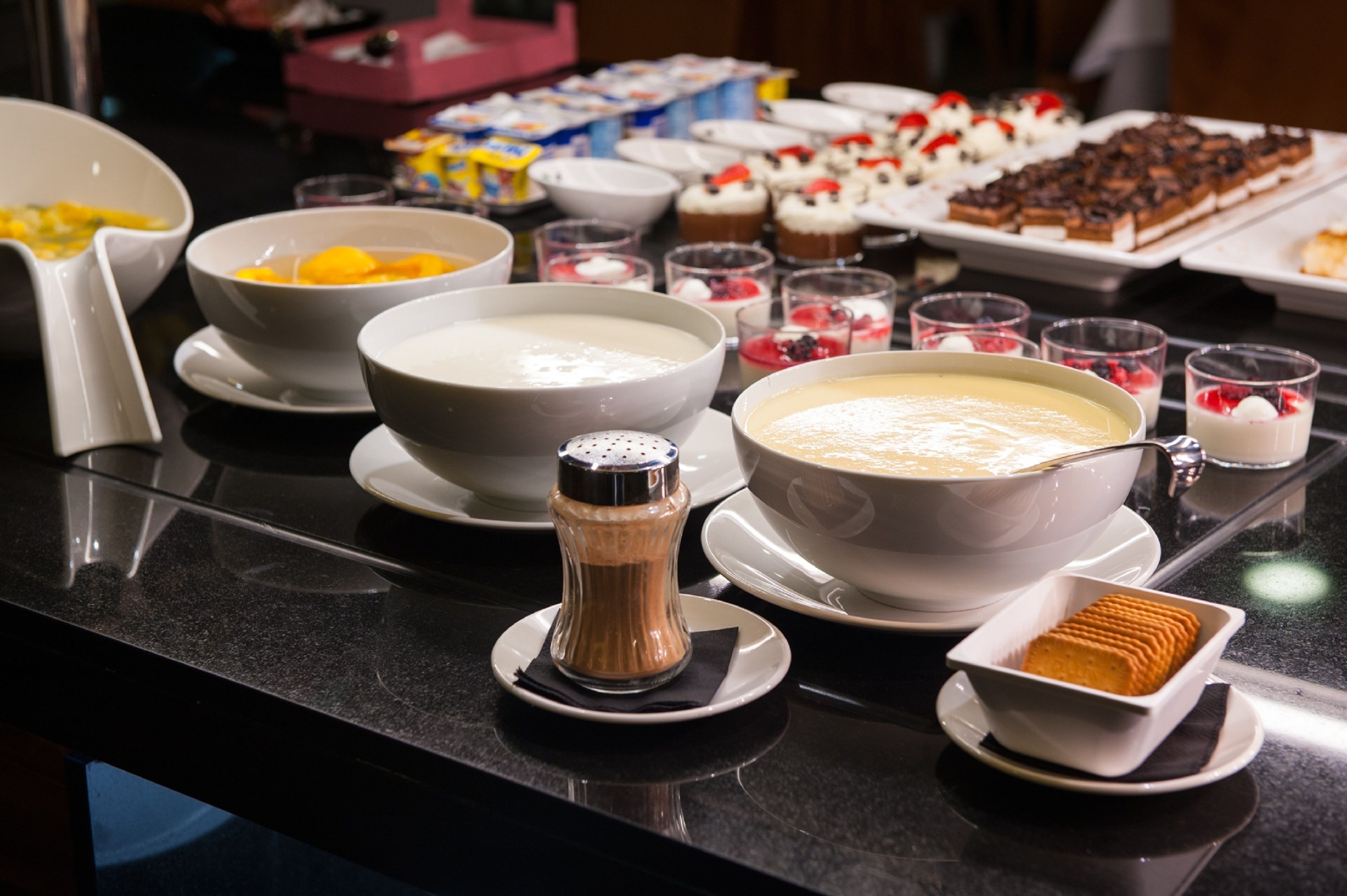 Una taula de buffet amb diversos plats, incloent-hi cuissines, postres i un salabrer i pebrer.