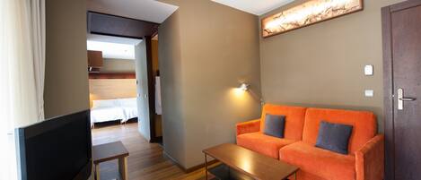 Una habitación de hotel moderna con sofá, televisión y un cuadro en la pared.