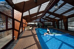 An indoor swimming pool with wooden deck and large windows. - SOMMOS Hotel Aneto (Benasque)