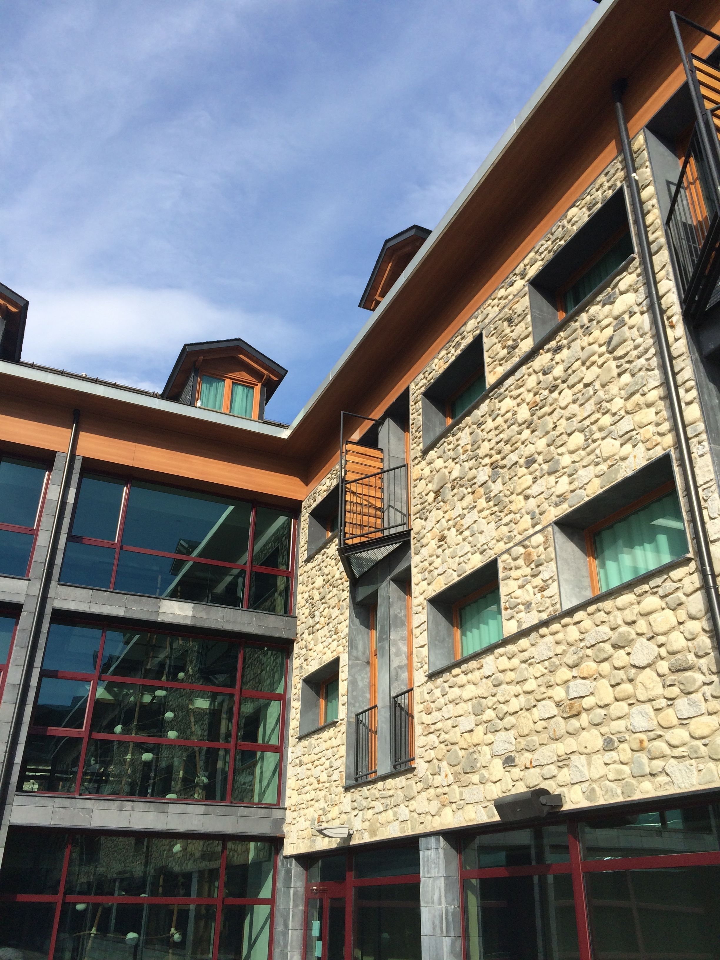A multi-story building with a stone facade, large windows, and a wooden upper level.