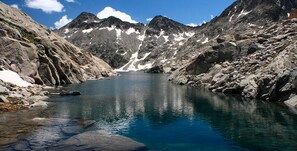 A serene mountain lake surrounded by rocky terrain and snow-capped peaks. - SOMMOS Hotel Aneto (Benasque)