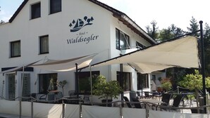 Hotel Waldseglier com área de estar ao ar livre e um alpendre coberto.