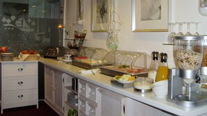 Disposição de buffet com diversos alimentos, uma máquina de café e um suporte para copos de vinho.