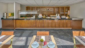 A modern bar area with a counter, shelves with bottles, and a seating area with tables and chairs. - City Express Plus by Marriott Ciudad de México Reforma El Ángel (Mexico City)