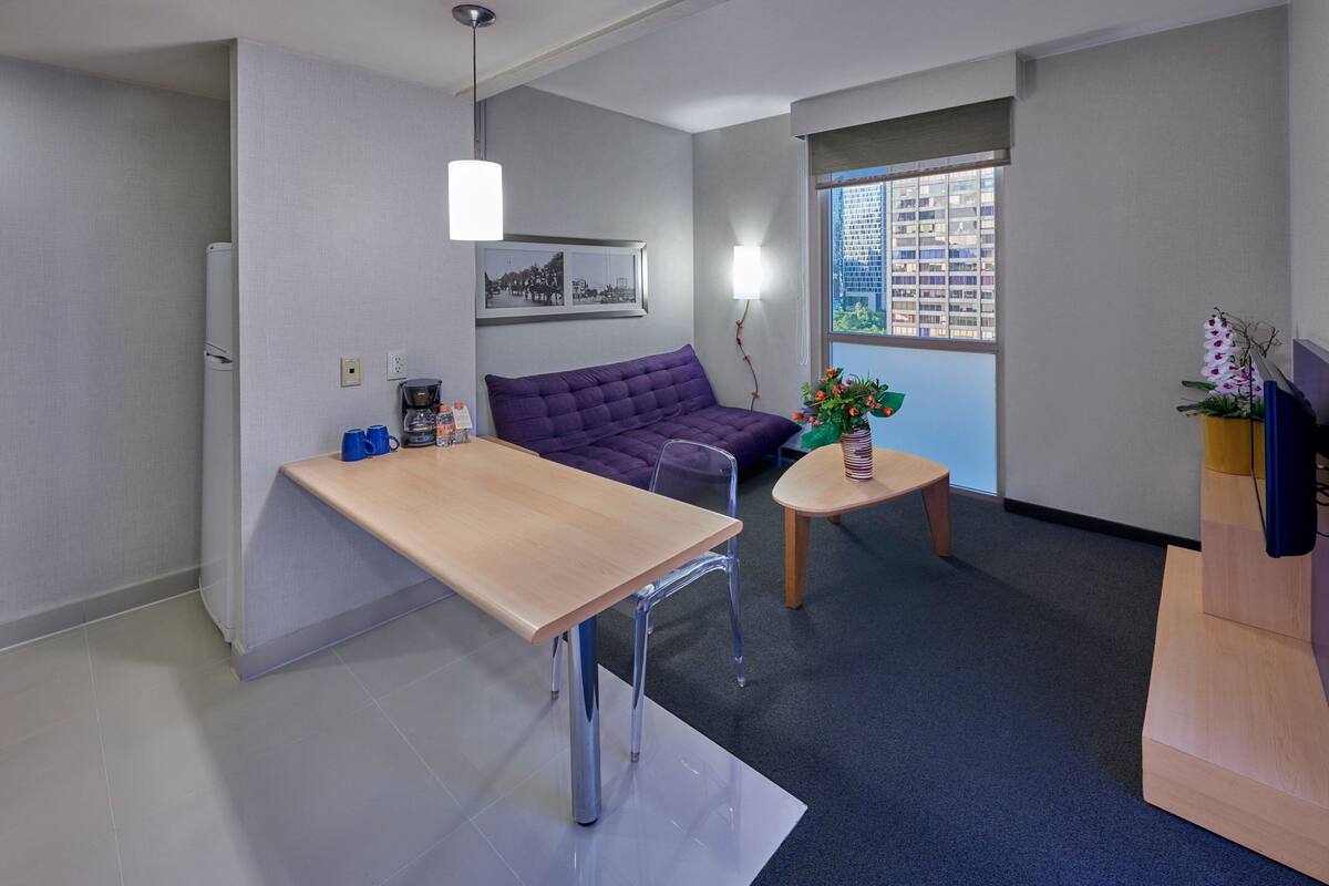 Un espacio habitable moderno y funcional con sofá, mesa de comedor y una mesita auxiliar.