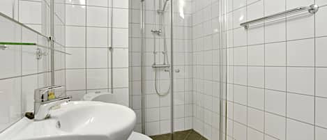 A bathroom with a white sink, toilet, and glass shower enclosure.