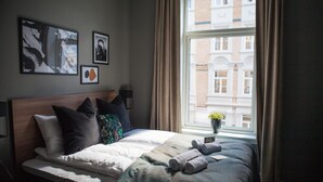 Un lit bien fait, avec des oreillers, une table de chevet avec une lampe et une fenêtre avec des rideaux.