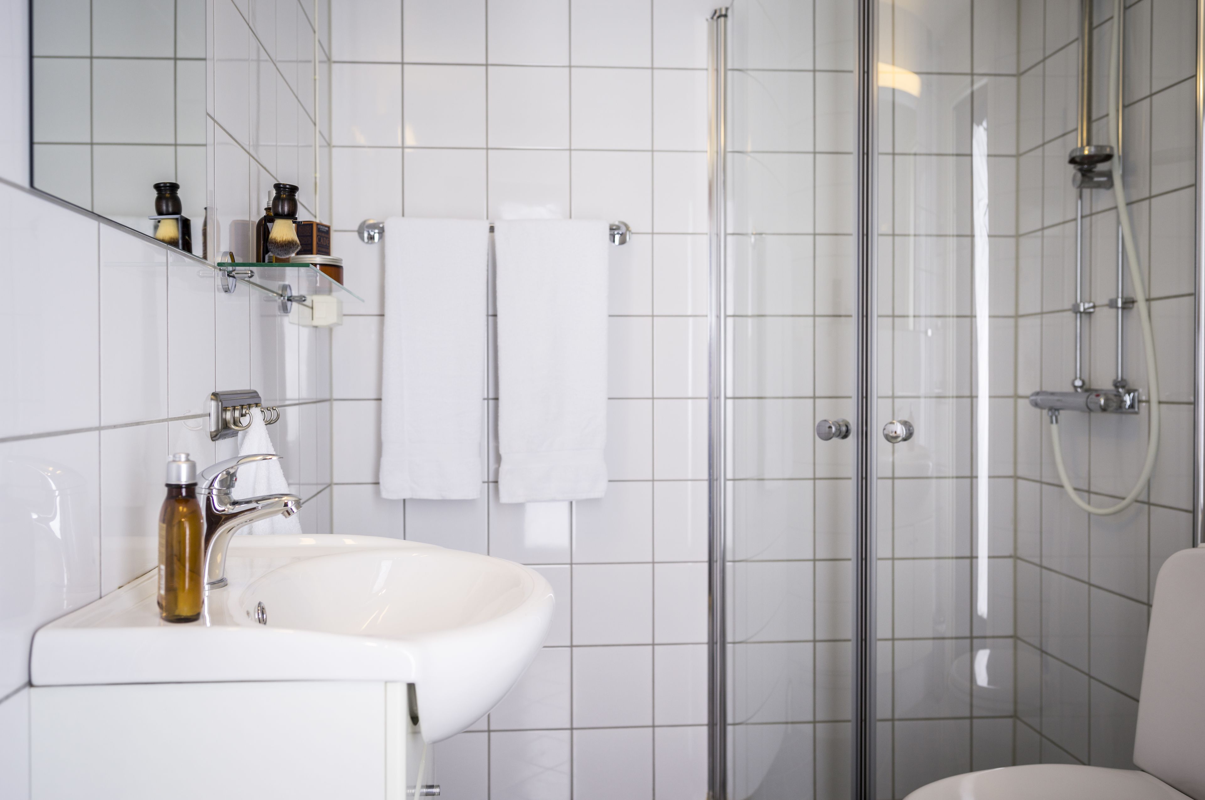 A modern bathroom with a white sink, mirror, and glass shower enclosure.