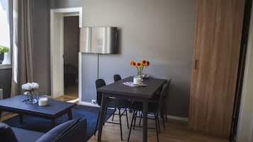 Un salon moderne avec une table à manger en bois foncé, des chaises noires, un canapé bleu et une table basse ornée d’un vase de fleurs.