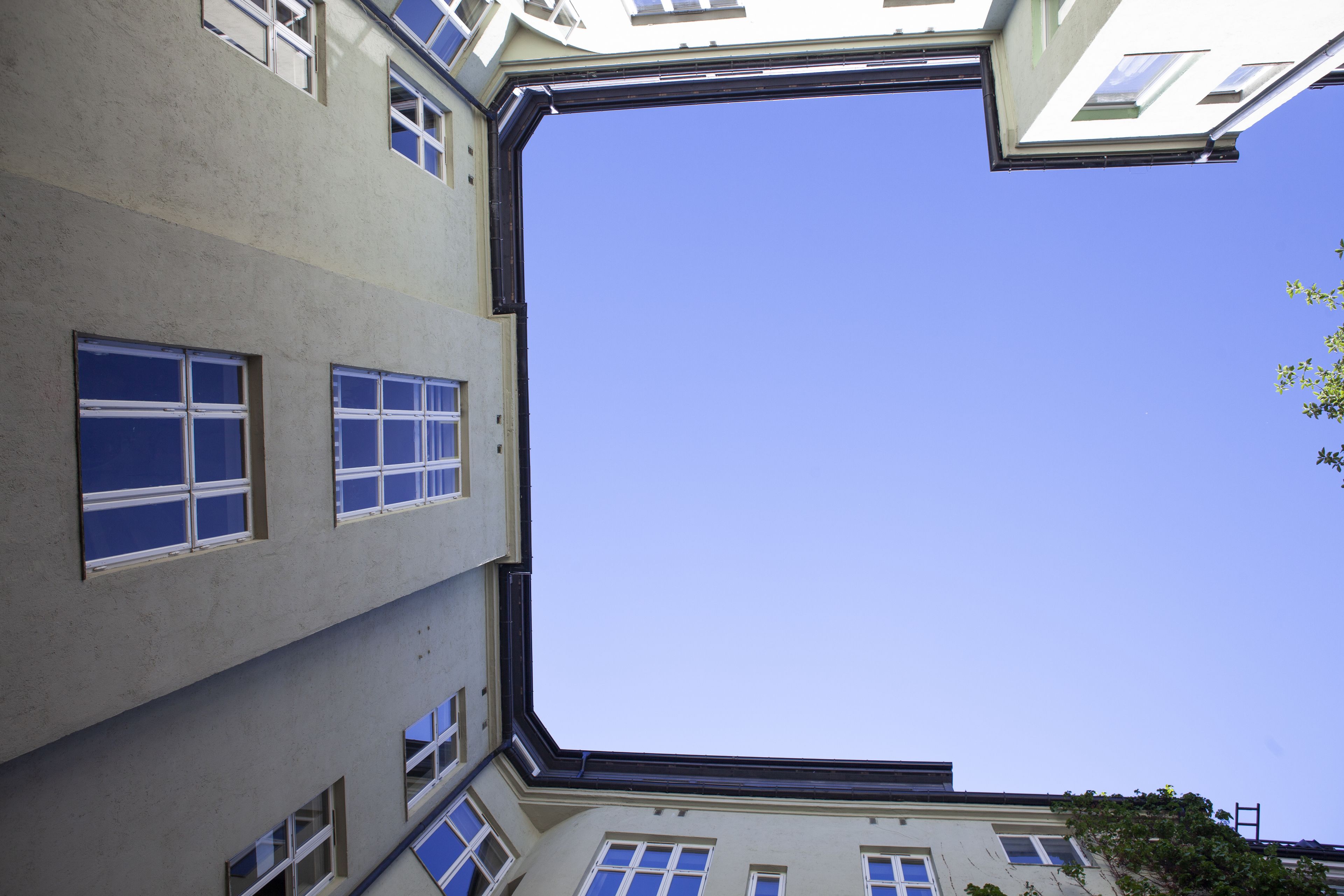 Vista lateral de un edificio con varias ventanas y un cielo azul despejado.