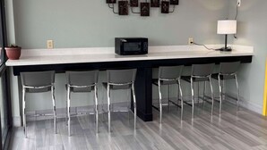 Une cuisine moderne dotée d’un long plan de travail, d’un four à micro-ondes et d’un luminaire fixé au mur.