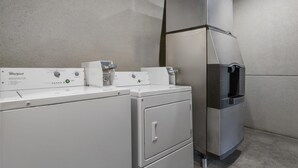 Un appareil combiné lave-linge et sèche-linge de la marque Whirlpool, doté d’un panneau de commande, d’un distributeur d’eau et d’un réfrigérateur en acier inoxydable.