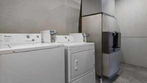 A Whirlpool washer and dryer unit with a control panel, a water dispenser, and a stainless steel refrigerator.