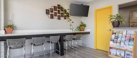 A modern bar area with a flat-screen TV, a yellow door, and a magazine rack.