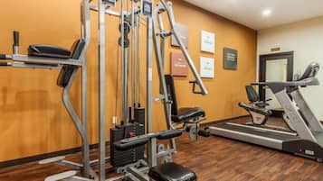 A gym with a variety of exercise equipment, including a multi-functional weight machine, a bench, and a treadmill.