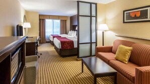 Quarto de hotel com cama, sofá, escrivaninha e televisão.