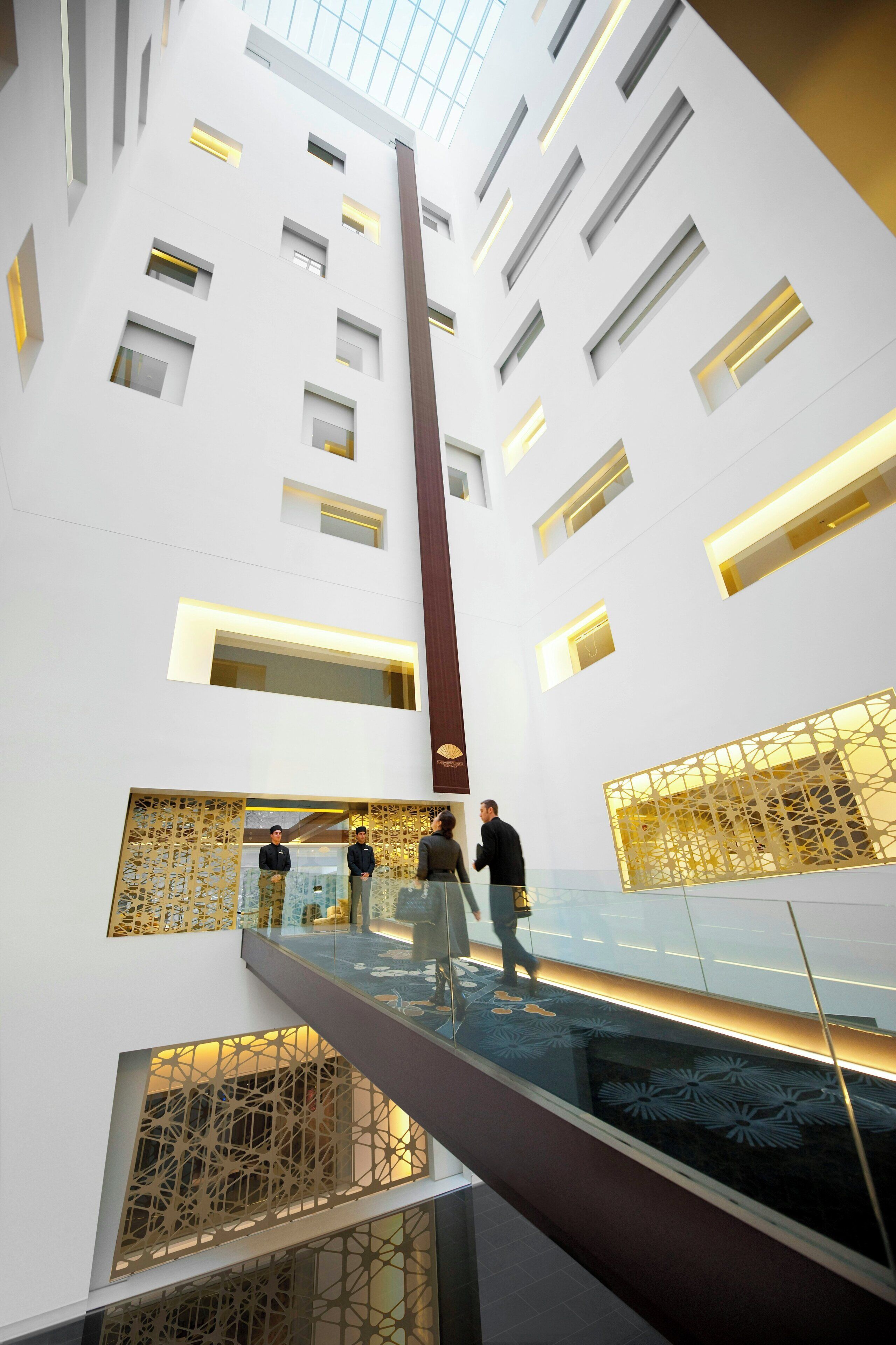A modern interior with a glass balustrade, a vertical column, and patterned wall panels.