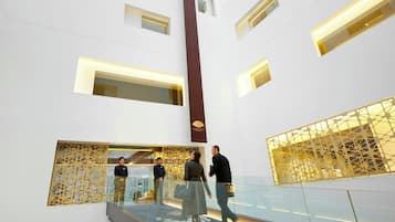 Un intérieur moderne avec une balustrade en verre, une colonne verticale et des panneaux muraux à motifs.