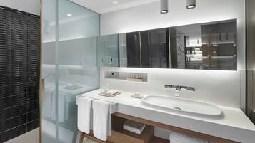 Un baño moderno con cabina de ducha de vidrio, un lavabo blanco y un espejo grande.