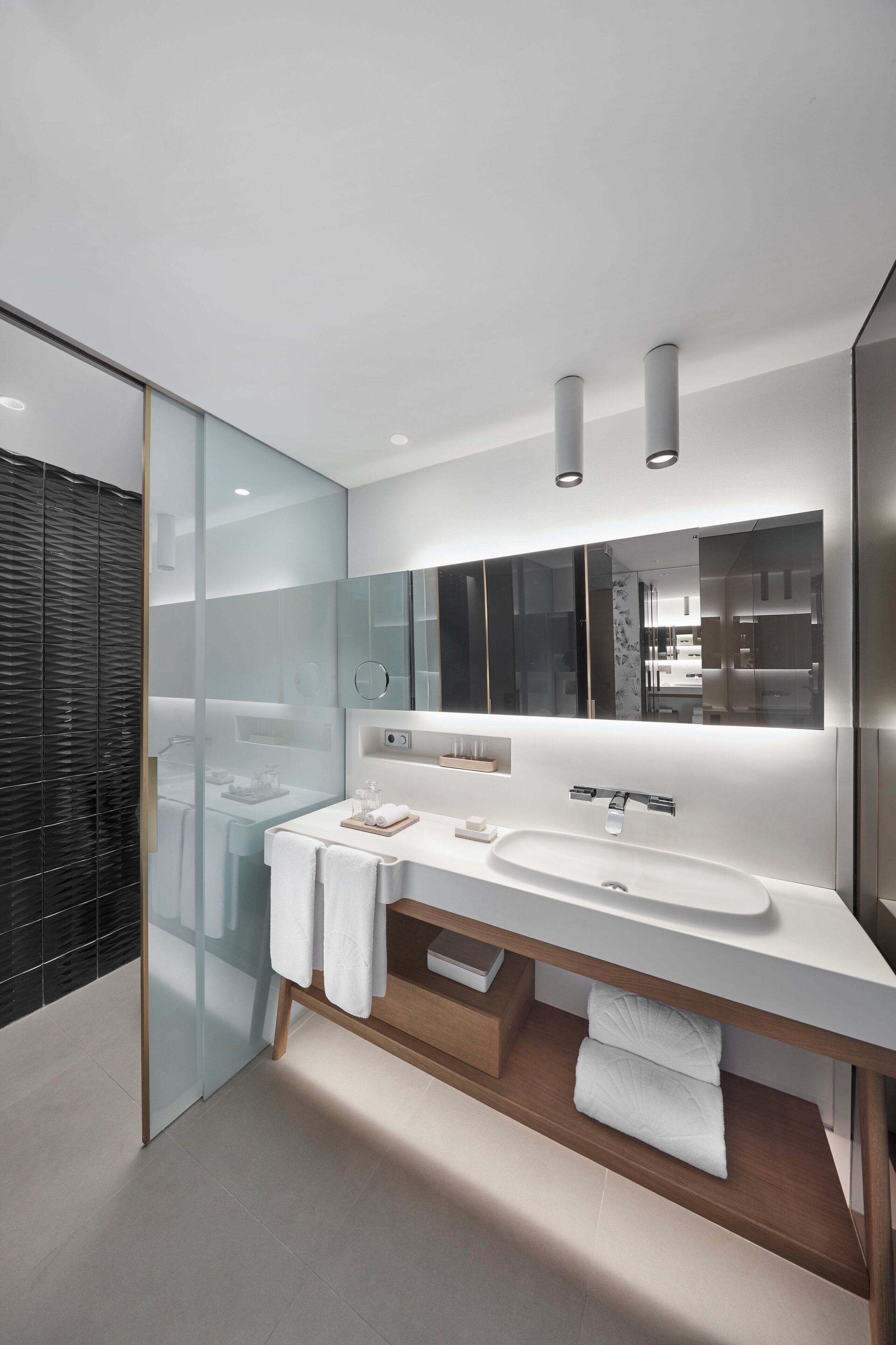 A modern bathroom with a glass shower enclosure, a large mirror, and a white sink.