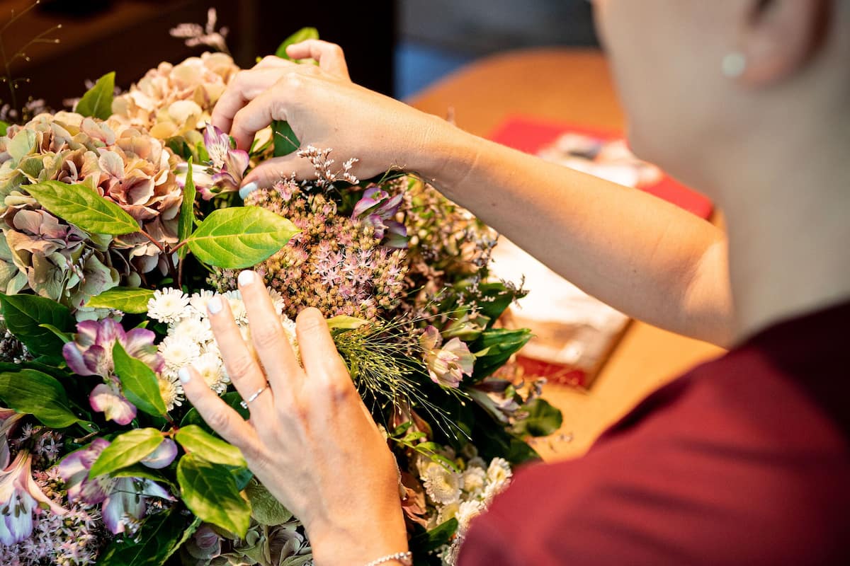 Uma pessoa organizando um buquê de flores.