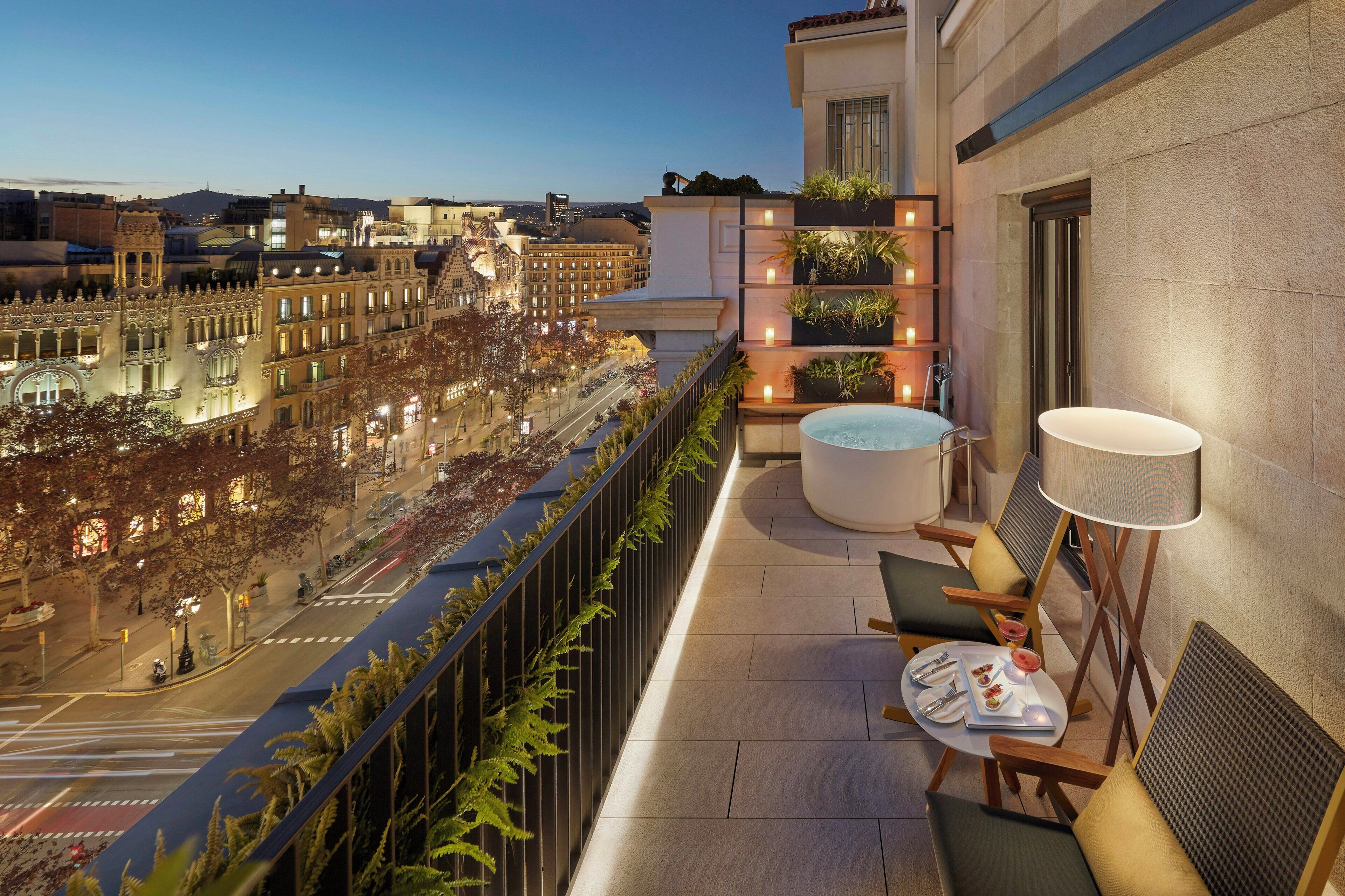 Un balcon donnant sur le paysage urbain, un coin salon avec une table et des chaises, et une grande fenêtre avec vue sur la rue.