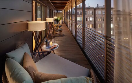 A balcony with a sofa, two lamps, and a small table with a candle.