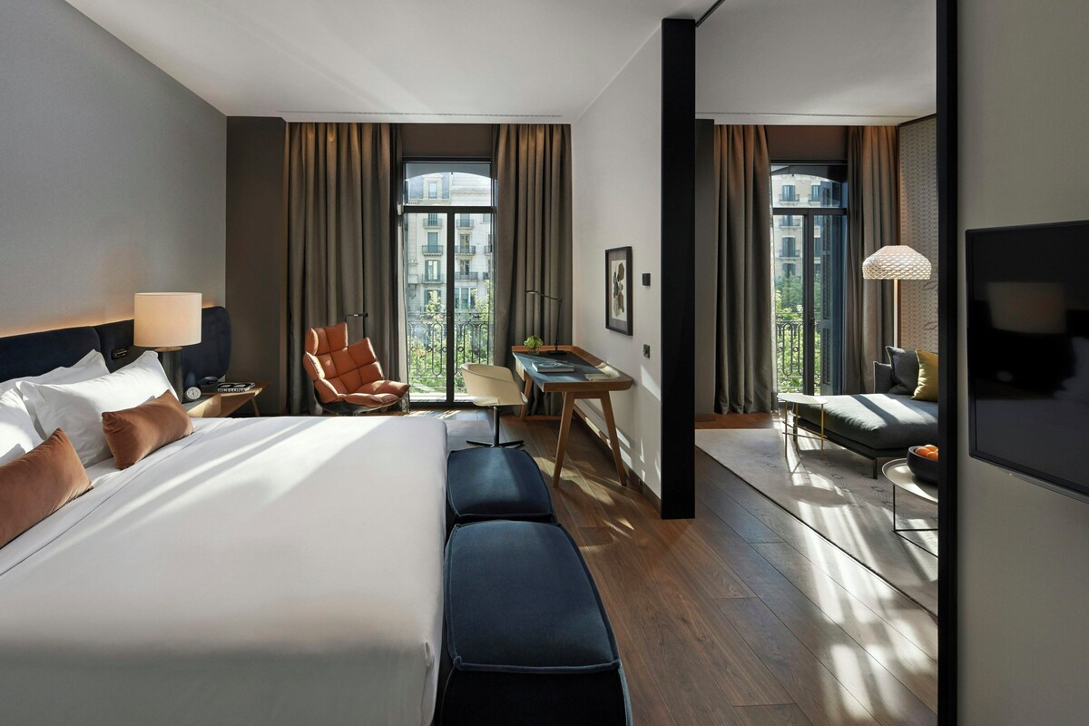 Una habitación de hotel con una cama grande, un escritorio, una silla, un sofá y un televisor.