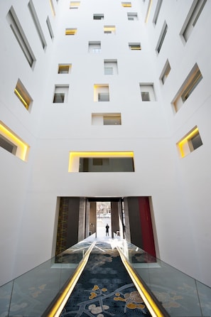 Interior moderno com corredor de vidro central, iluminação embutida e ladrilhos estampados.